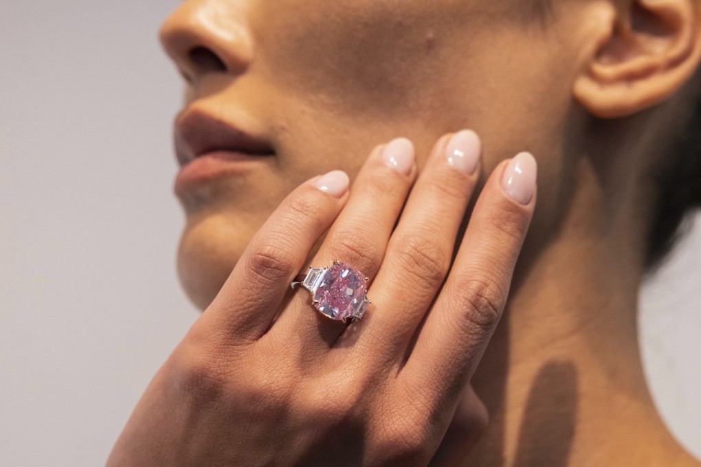 A woman poses with a 10.57 carat pink diamond at Sotheby’s in New York in March. Photo: AP