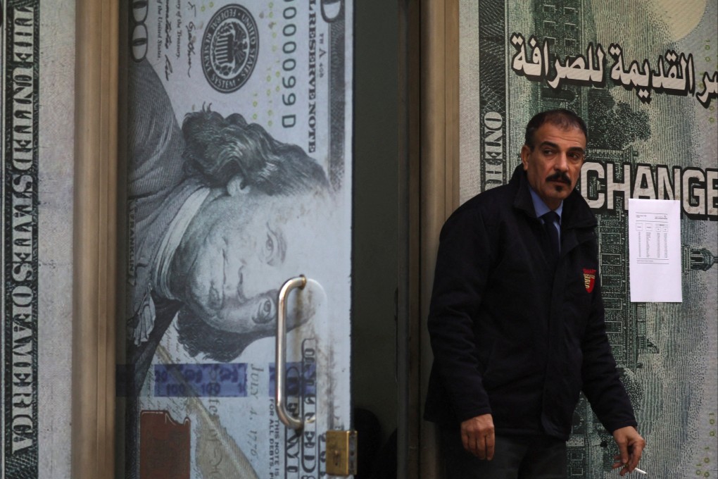 A security guard stands next to a currency exchange bureau advertisement in Cairo, Egypt, on January 17. The logical end to the US debt binge is the collapse of the dollar and rampant inflation. Photo: Reuters
