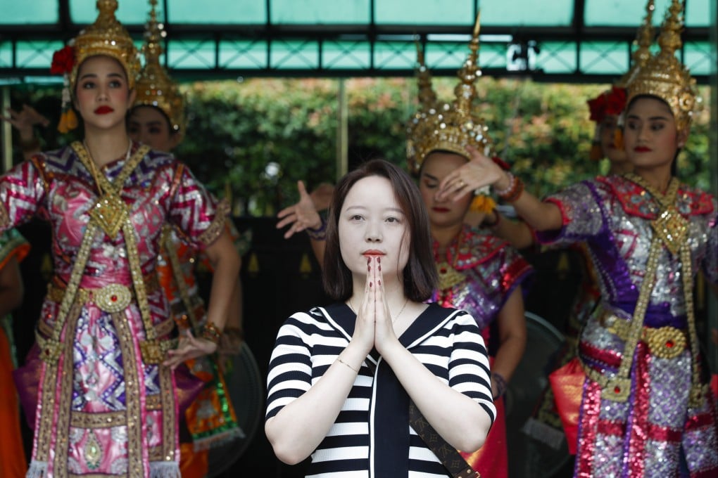 A Chinese tourist praying in front of Thai dancers at the popular Erawan Shrine in Bangkok on Friday. Photo: EPA-EFE