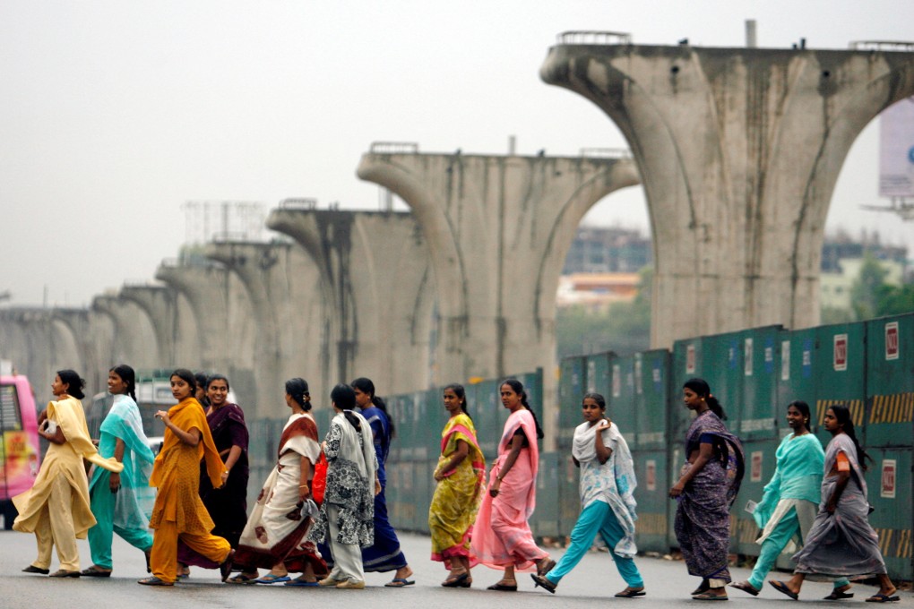 Women walk past the a highway under construction in Bangalore, India. Photo: Reuters