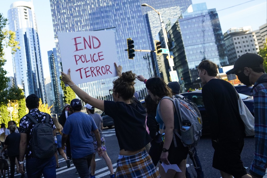 People cross the street as they walk to the Seattle Police Department’s West Precinct to protest against an officer, who made callous remarks about the death of an Indian woman. Photo: AP