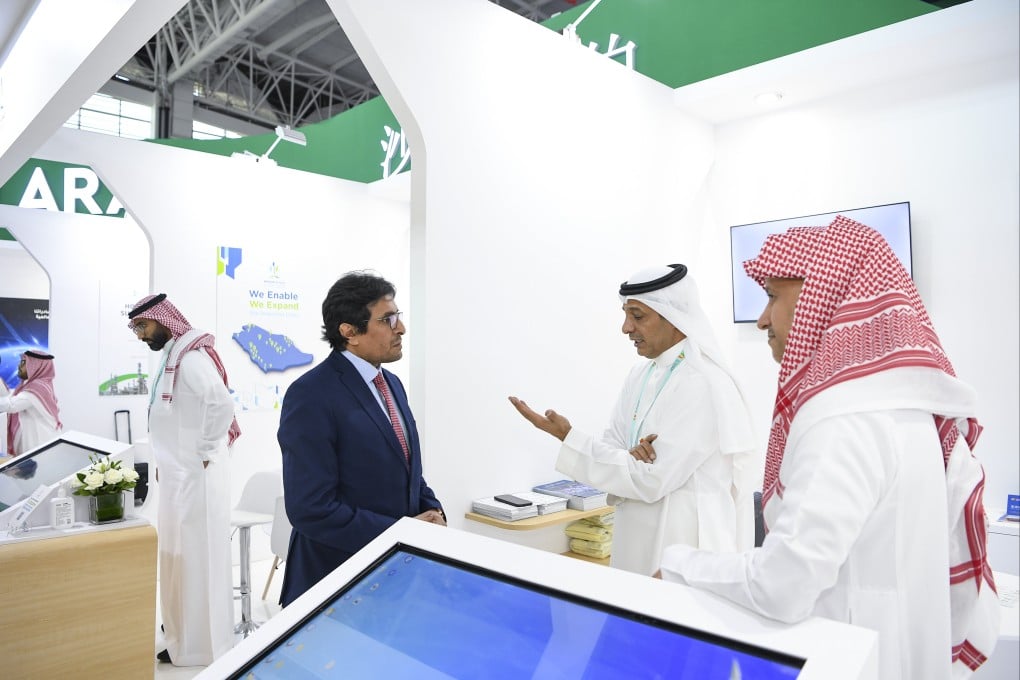 A guest talks with exhibitors at the Saudi booth during the expo. Photo: Xinhua
