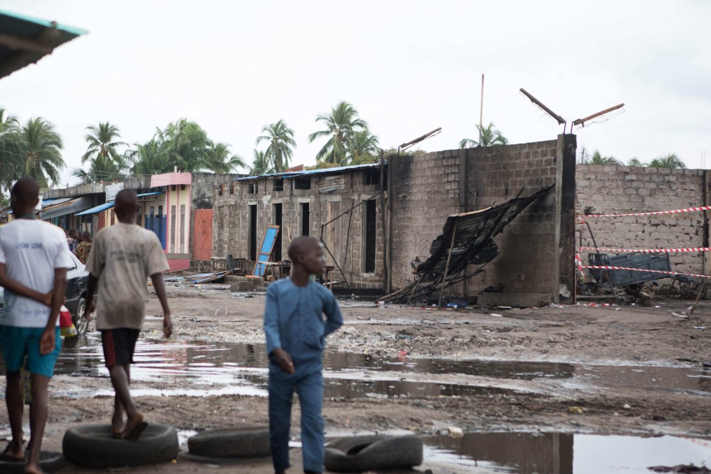 People walk past the burnt remains of a fuel depot near the Benin-Nigeria border in Seme-Krake, Benin on Sunday. Photo: AFP