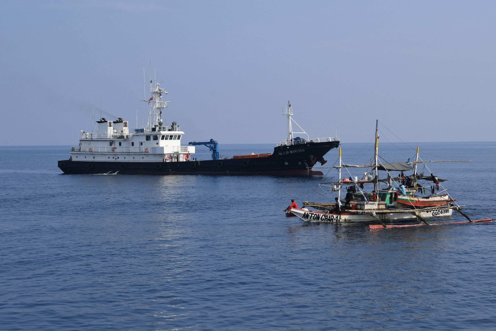 A Philippine fishing boat sailing past a Chinese militia ship near the Chinese-controlled Scarborough Shoal in the South China Sea last Wednesday. Photo: AFP