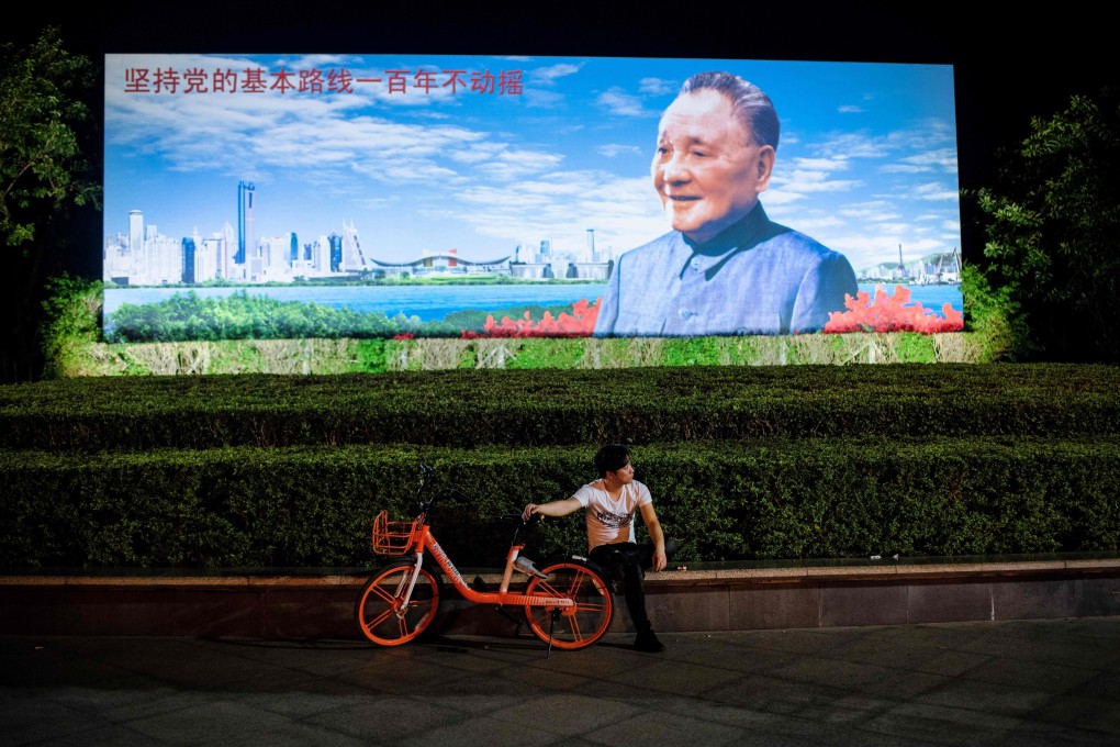 A man with a bike-share rental sitting in front of a poster of former Chinese leader Deng Xiaoping in Shenzhen on November 8, 2018. Photo: AFP