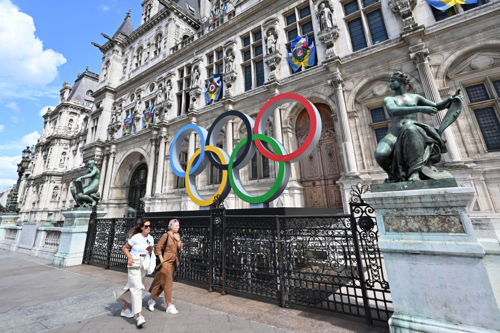 People walk past the Olympic rings in front of the Paris City Hall on August 18, 2023. Hotel prices in the French capital have soared ahead of the 2024 Olympics. Photo: Getty Images