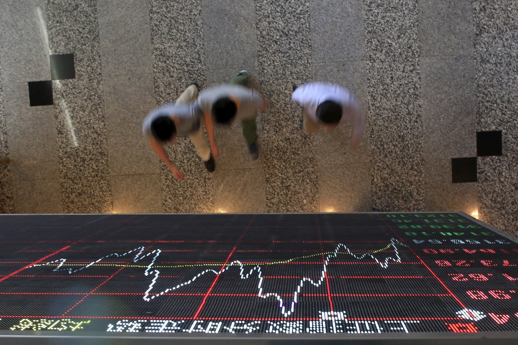 People seen walking under an electronic board showing the Shanghai Stock Exchange data in Lujiazui financial district. Photo: Reuters