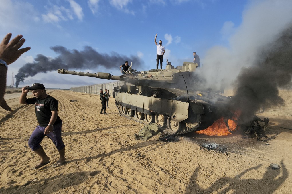 Palestinians celebrate around a destroyed Israeli tank at the Gaza Strip fence on Saturday. Photo: AP
