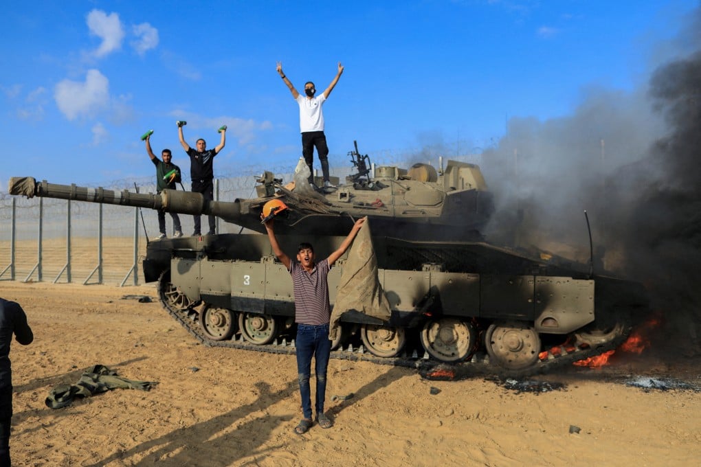 Palestinians celebrate as an Israeli tank burns at the Israeli side of Israel-Gaza border. Photo: Reuters