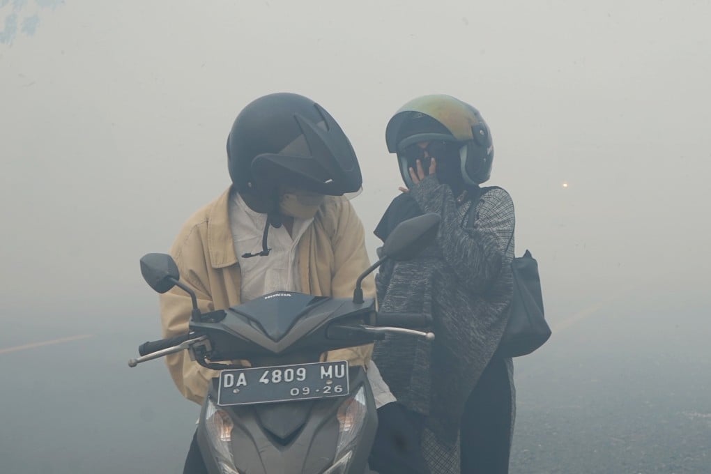 People cover their faces while passing through smoke from peatland fires in Indonesia’s South Kalimantan late last month. Photo: Xinhua