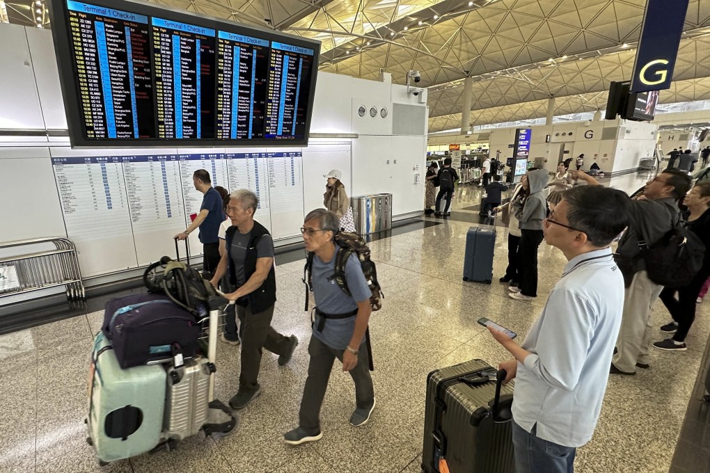 Travellers at Hong Kong International Airport keep an eye on flight information during the typhoon. Photo AP