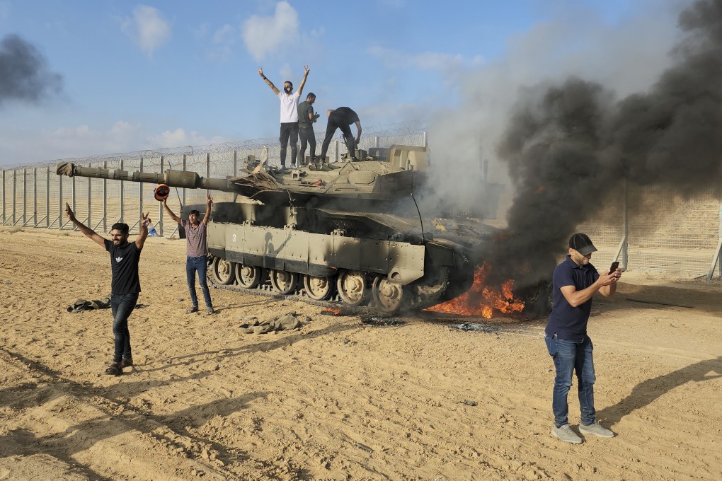 Palestinians celebrate by a destroyed Israeli tank at the Gaza Strip fence east of Khan Younis on Saturday. Photo: AP