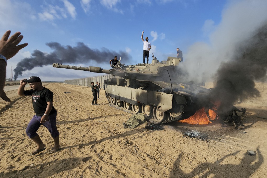 Palestinians celebrate by a destroyed Israeli tank at the Gaza Strip fence east of Khan Younis on Saturday. Photo: AP