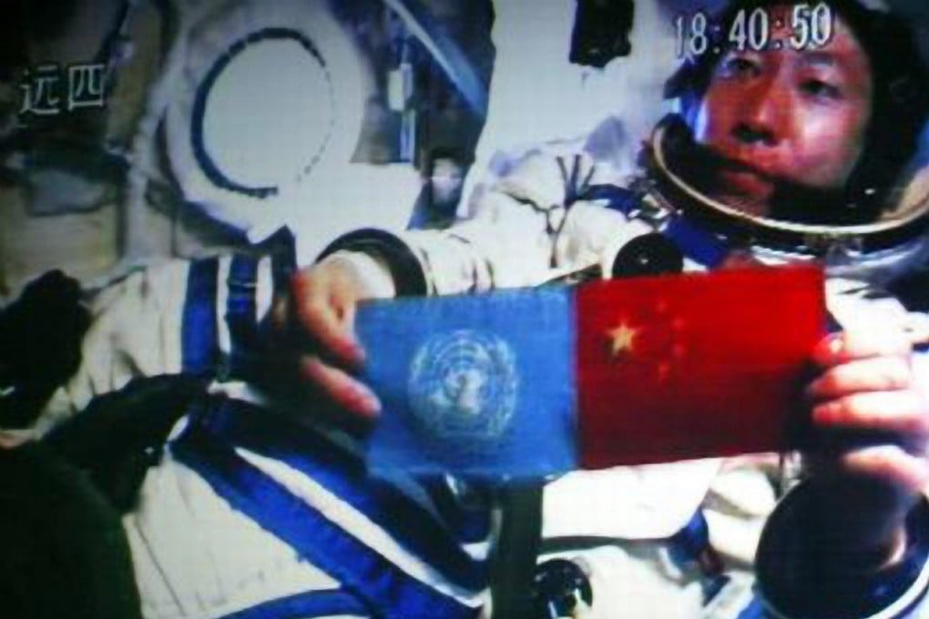In a show of brotherhood, astronaut Yang Liwei holds up the flags of China and the UN while orbiting the Earth. Photo: sina