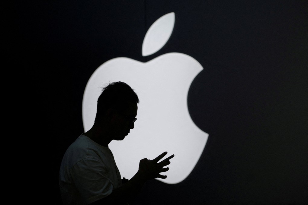 A man checks his phone outside an Apple store in Shanghai, China. Photo: Reuters