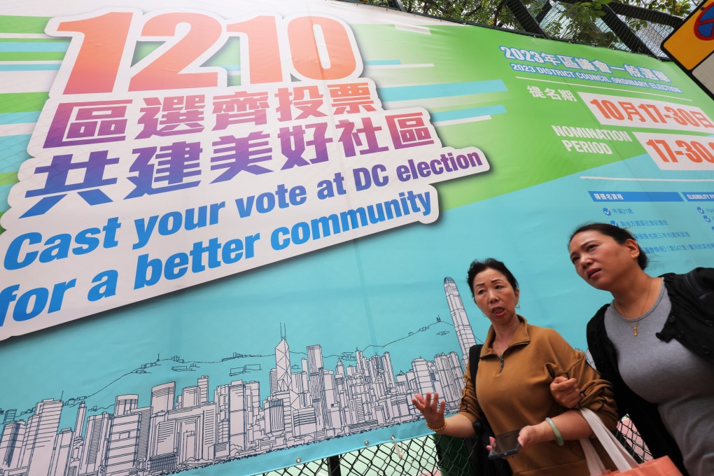 Hongkongers walk past a poster promoting the District Council Election in December. Photo: Jelly Tse