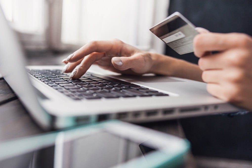 A person holding a credit card and a laptop for an online transaction. Photo: Shutterstock