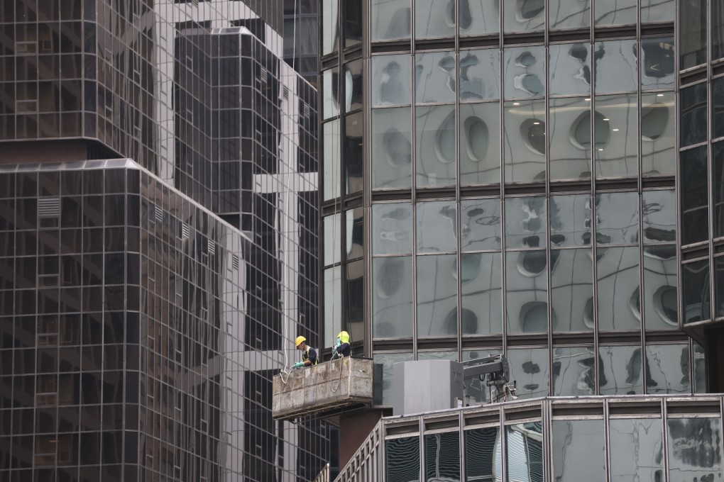Window cleaners work on a high-rise building in Hong Kong’s Central. A sluggish economy and interest rate pressure will hamper the city’s investment market and overall business environment, the Colliers report says. Photo: May Tse