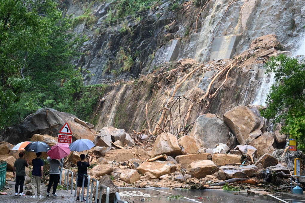 Plainclothes officials and police look at a landslide covering a road in Shau Kei Wan on September 8, following heavy rains. Photo: AFP