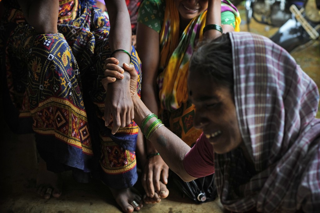 A woman holds the hand of a relative after a landslide washed away houses and their occupants in western Maharashtra state in India in July. Photo: AP