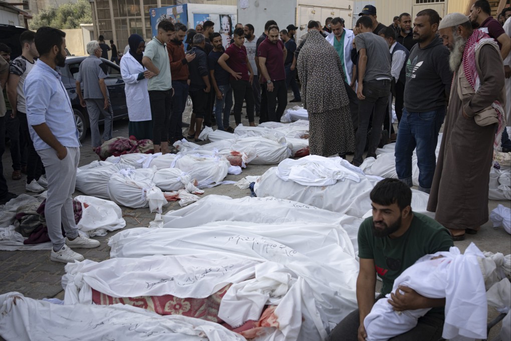Friends and relatives stand on Sunday by the bodies of Palestinians killed in Israel’s bombardment of  Gaza. Photo: AP