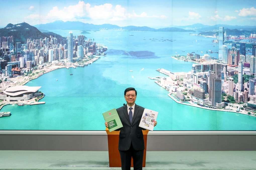 Chief Executive John Lee poses with copies of his policy address against a new stage backdrop. Photo: Yik Yeung-man