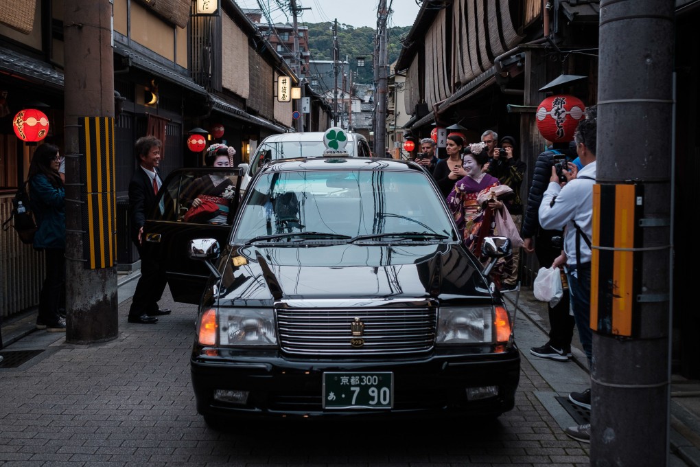 Tourists surround two maiko - apprentice geisha in Kyoto - as they get into a taxi in the Gion area in April 2019. As tourists return to Japan at almost pre-pandemic levels, the city is once again dealing with the problems of overtourism, including traffic, littering and bad behaviour. Photo: Getty Images