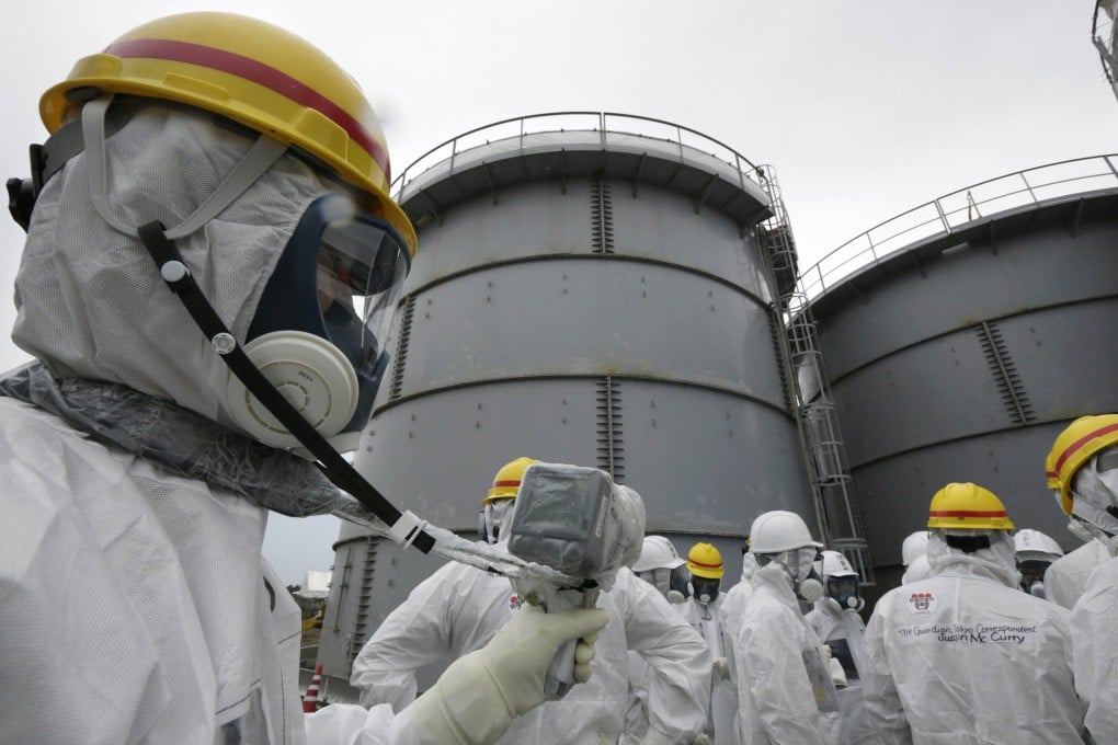 A Tokyo Electric Power Co employee wearing a protective suit and mask uses a survey meter near storage tanks for radioactive water. Photo: Reuters/File