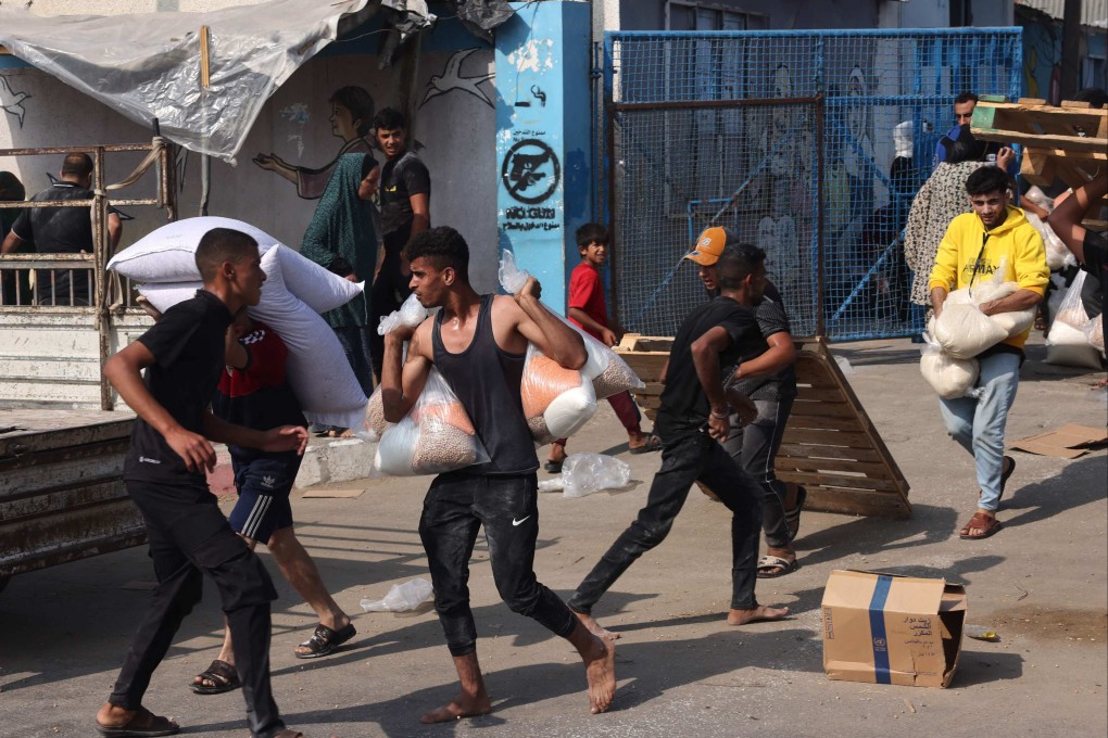 Palestinians collect bags of dried food from a UN-run aid supply centre. Photo: AFP
