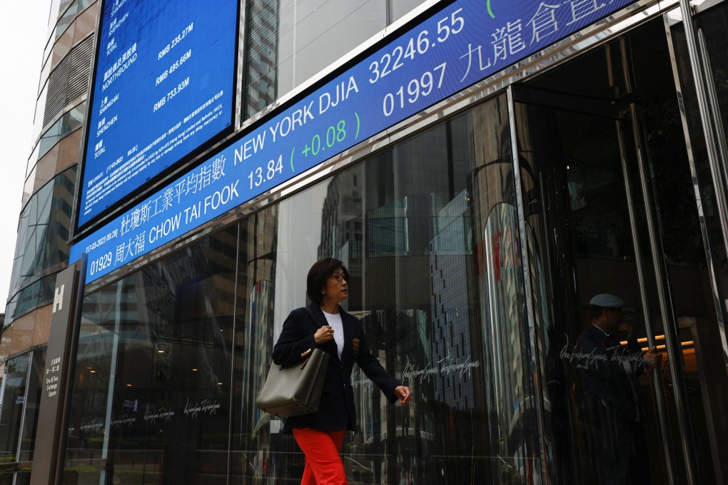 A woman walks past a screen displaying the Hang Seng Index outside the Exchange Square in Central. Photo: Reuters