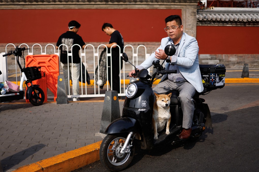 A man rides a scooter with a dog in Beijing on October 17. Raising a pet dog has become a way of life in China. Photo: Reuters