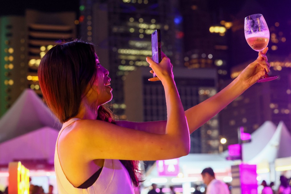 A woman takes a photo of her glass of wine at the Hong Kong Wine and Dine Festival at the Central harbourfront on October 26. Winemakers are facing pressure on multiple fronts with climate change reducing crop yields and changing tastes among young people driving down consumption. Photo: Dickson Lee
