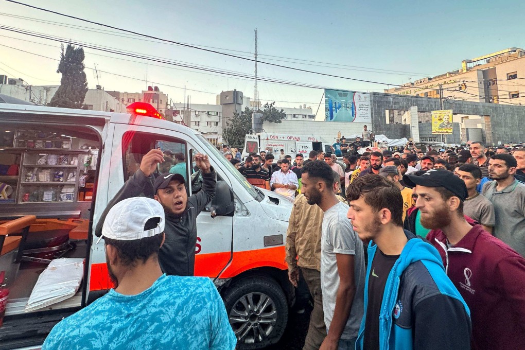 People gather around an ambulance damaged in a reported Israeli strike in front of al-Shifa hospital in Gaza City on Friday. Photo: AFP