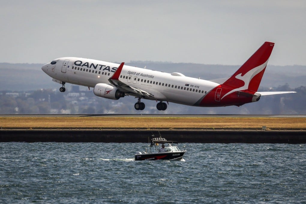 A fisherman drives his boat on Botany Bay as a Qantas Airways Boeing 737-838 airplane takes off at Sydney’s Kingsford Smith international airport. Photo: AFP