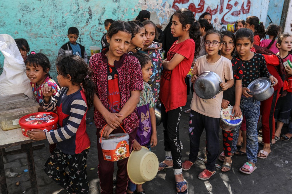 Palestinian children displaced from the northern Gaza Strip line up on Thursday to get hot meals prepared and distributed by volunteers. Photo: dpa