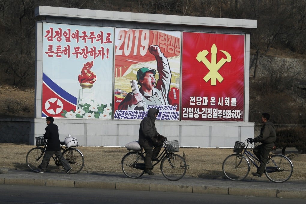 North Korean men ride their bicycles past propaganda banners in Pyongyang. Photo: AP