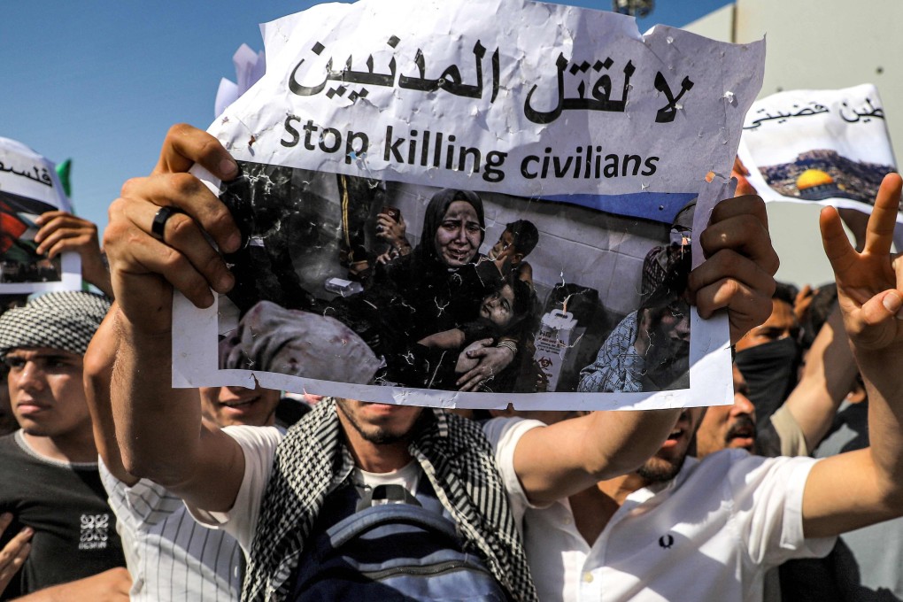 Protesters on the Egyptian side of the Rafah border crossing with Gaza hold placards denouncing the killing of civilians during a rally at the site last month. Photo: AFP