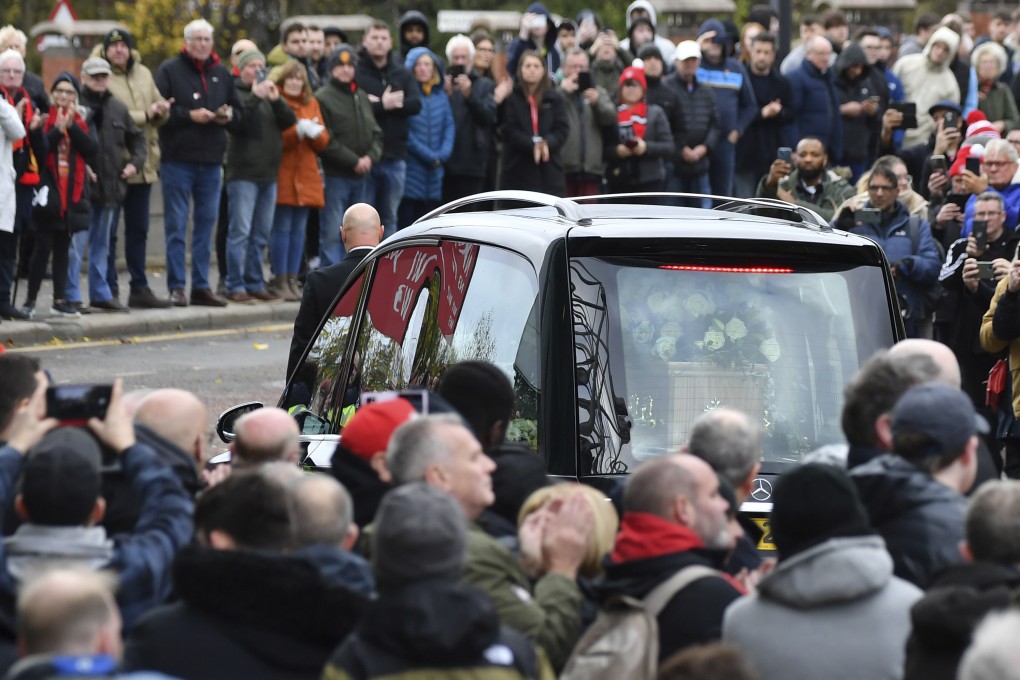 The cortege of English soccer icon Bobby Charlton passes a street lined with fans on its way to his funeral service in Manchester, England, on Monday. Photo: AP