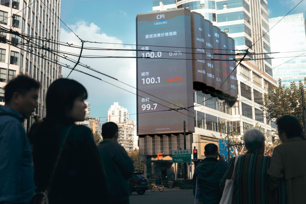 People stand on the street beneath a large screen showing the latest market and economic data, in Shanghai on October 20. Photo: EPA-EFE