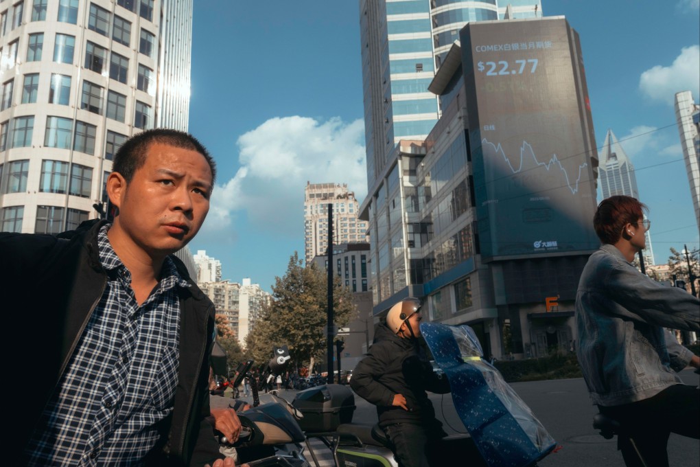 People pass beneath a large screen showing the latest stock exchange and economy data in Shanghai on October 20, 2023. Photo: EPA-EFE