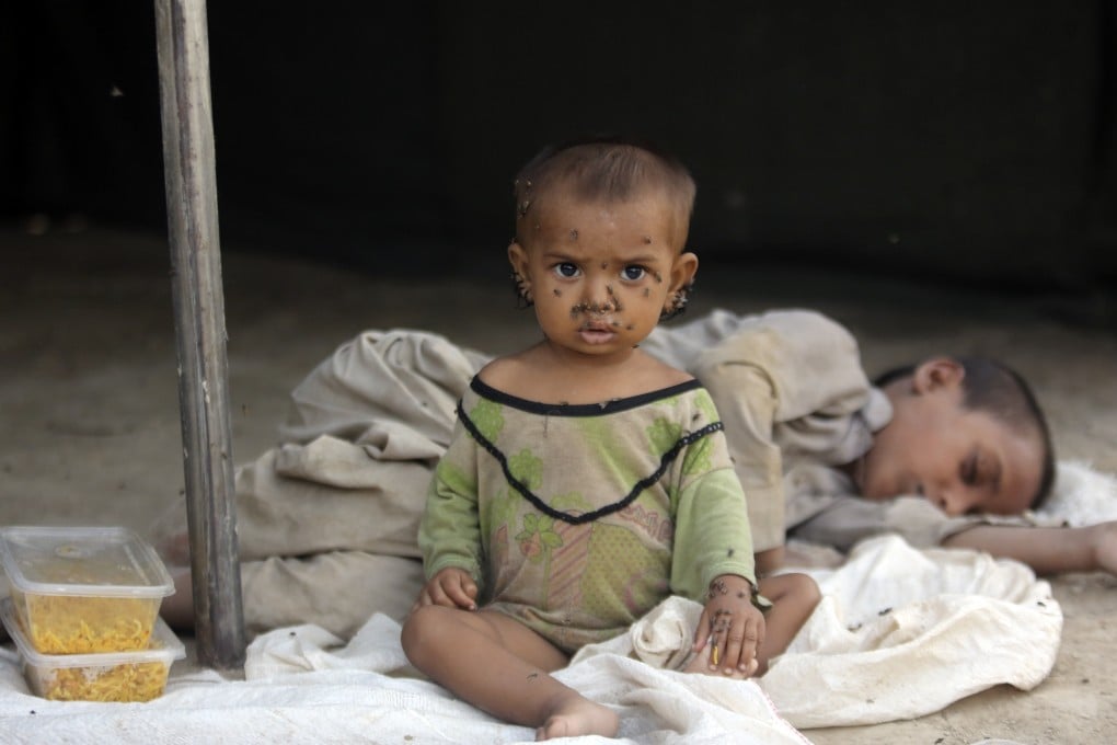 Children in Pakistan displaced by flooding from monsoon rains sit in a temporary tent housing camp for flood victims in September 2022. Photo: AP