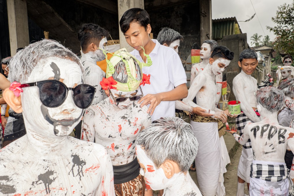 Pande Putu Aditama (10) stands with his friends as his hair is painted ahead of the Ngerebeg ritual, in Tegalalang village, Bali, Indonesia, on September 6, 2023. These photos of the parade show the bright colours used to help children resemble the supernatural beings and demons of Niskala (the unseen world). Photo: Agung Parameswara
