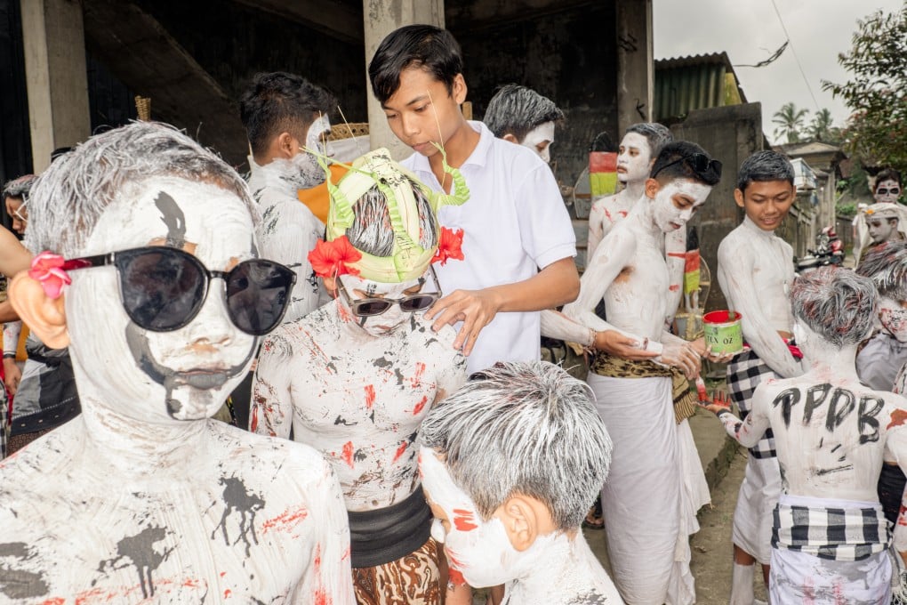 Pande Putu Aditama (10) stands with his friends as his hair is painted ahead of the Ngerebeg ritual, in Tegalalang village, Bali, Indonesia, on September 6, 2023. These photos of the parade show the bright colours used to help children resemble the supernatural beings and demons of Niskala (the unseen world). Photo: Agung Parameswara
