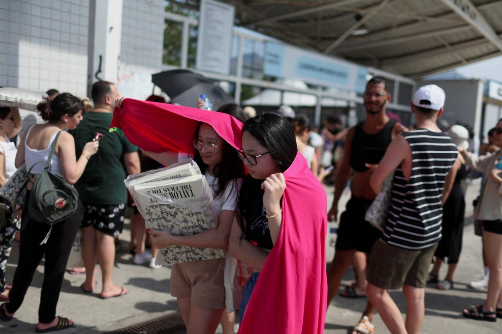 Women protect themselves from the sun with a blanket as they stand in a queue outside the Nilton Santos stadium where the Taylor Swift concert takes place. Photo: Reuters