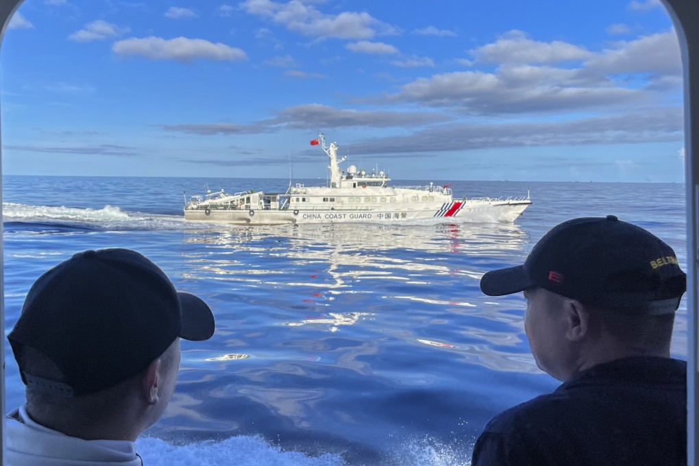 Philippine coastguard personnel watch as a Chinese coastguard ship manoeuvres beside their vessel near a disputed South China Seal shoal earlier this month. Photo: AP