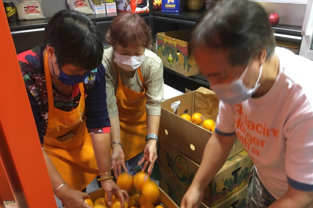 Foodlink Mart’s store manager (right) and two elderly beneficiaries, who are also volunteers, sort fruits delivered to the store from supermarkets. Photo: Cindy Sui