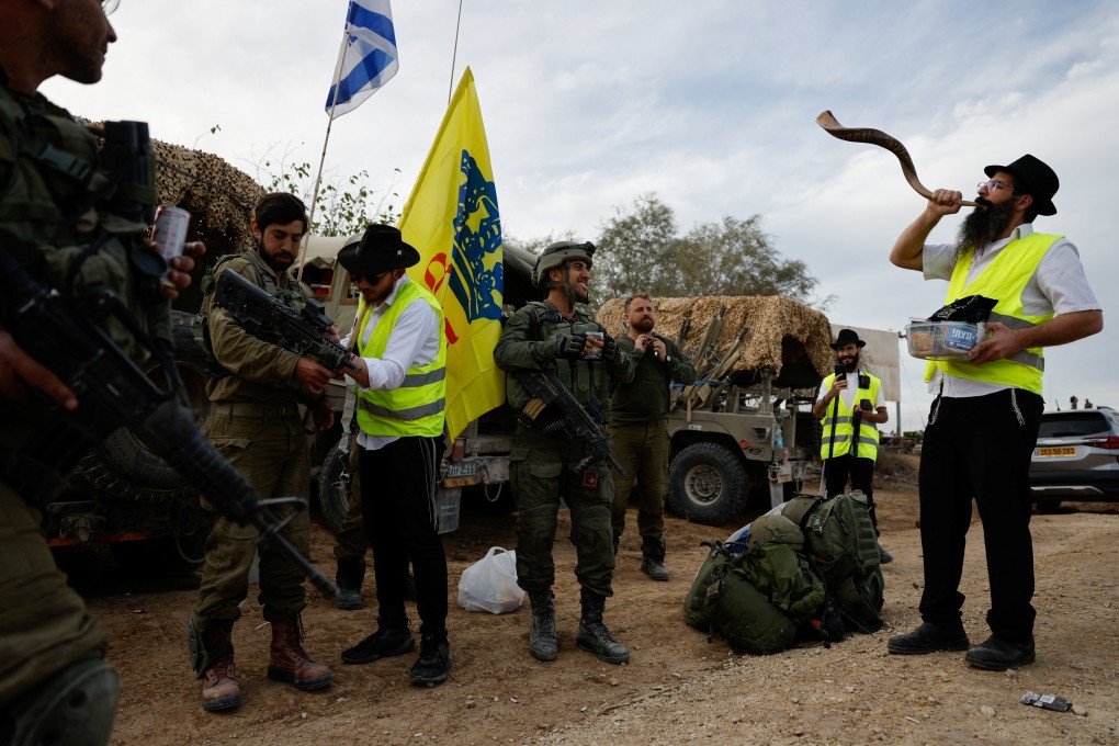 A man blows a shofar next to Israeli soldiers who celebrate after returning from Gaza, near Israel’s border with Gaza in southern Israel. Photo: Reuters