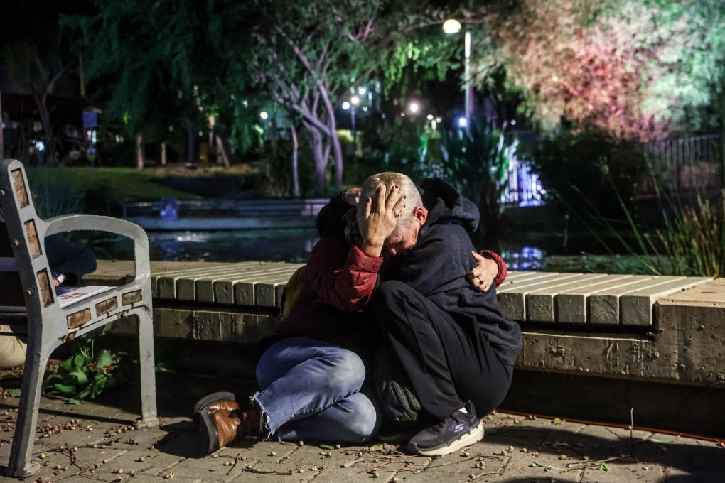People take cover in Tel Aviv, Israel, as a siren sounds signalling incoming rockets from Gaza, during a protest calling on the UN to assist children being held hostage by Hamas. Photo: Reuters