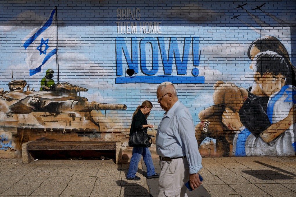 People walk past graffiti calling for the return of hostages in Kfar Saba, Israel on Thursday. Photo: AP