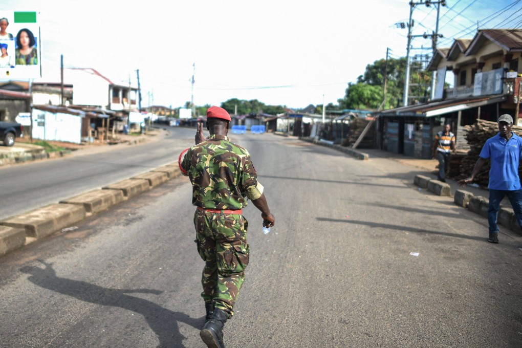 A soldier with the Sierra Leonean military police greets a man along an empty road in Freetown on November 26. Photo: AFP